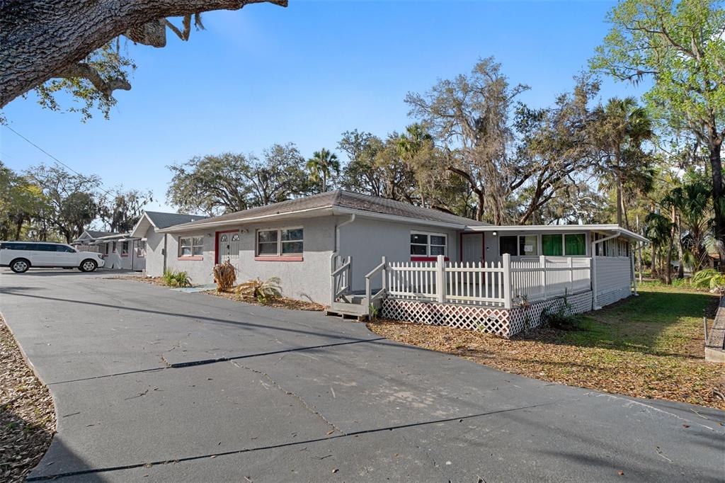 A single-story gray house features a white picket fence deck and a large paved driveway — 639 NE 1ST STREET, CRYSTAL RIVER, FL