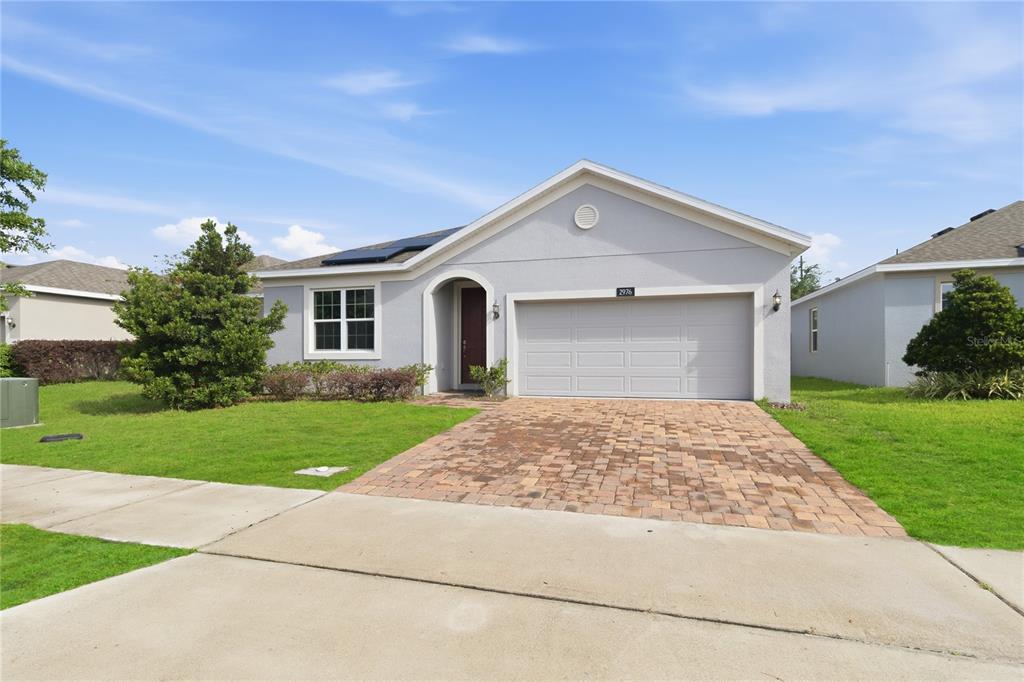 A single-story house with a gray stucco exterior, a two-car garage, and a paver driveway — 2976 NOTTEL DRIVE, ST CLOUD, FL
