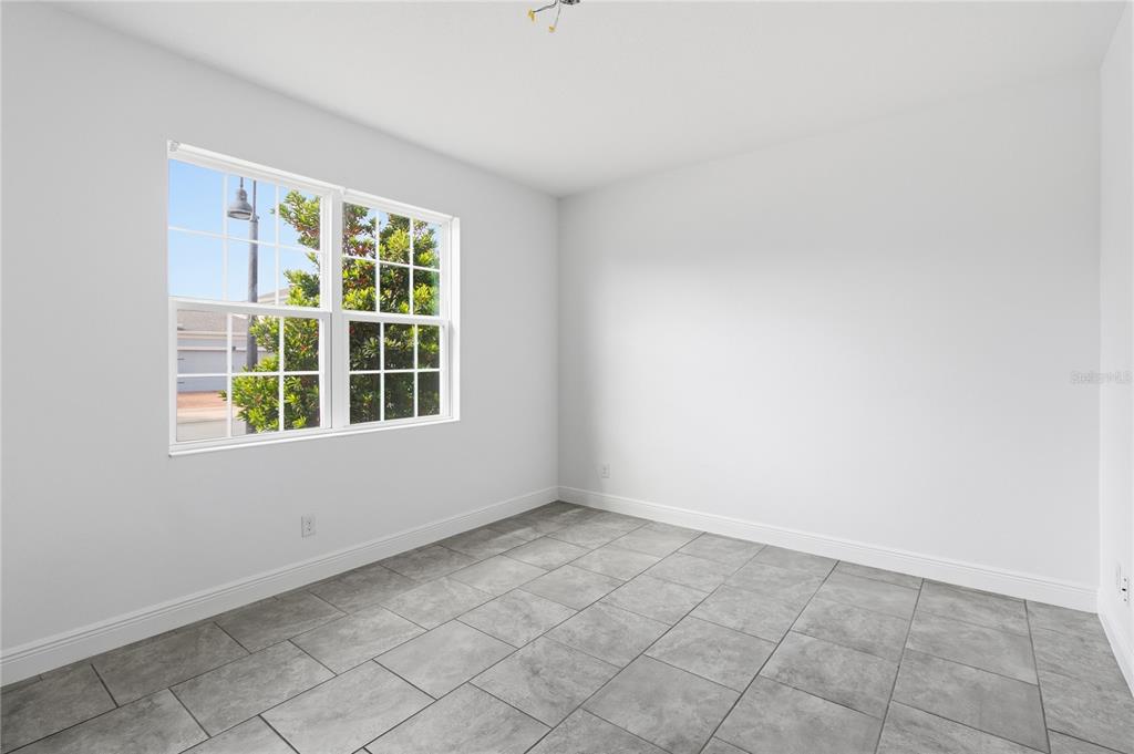 An empty room with white walls, gray tile flooring, and a window overlooking a street — 2976 NOTTEL DRIVE, ST CLOUD, FL
