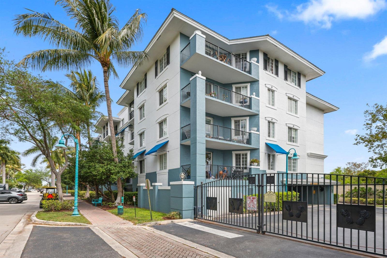 A multi-story apartment building with blue and white exterior walls and gated parking access — 255 NE 3rd Avenue Unit 407, Delray Beach FL 33444, DELRAY BEACH, FL