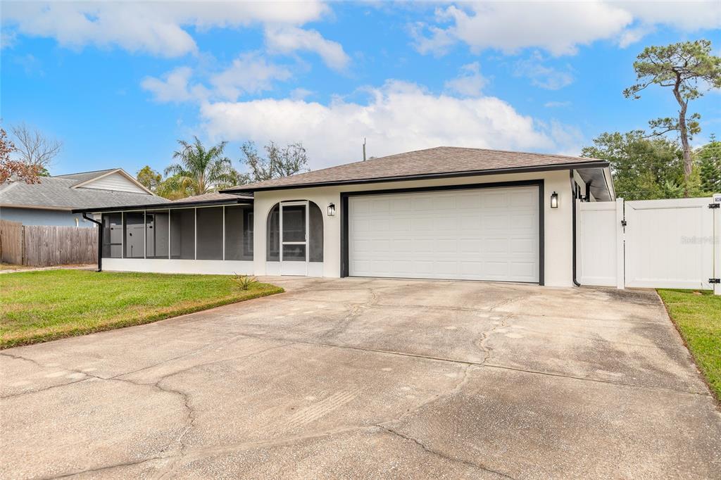A single-story house with a white garage door, a screened-in porch, and a concrete driveway — 2509 MILTON AVENUE, NEW SMYRNA BEACH, FL