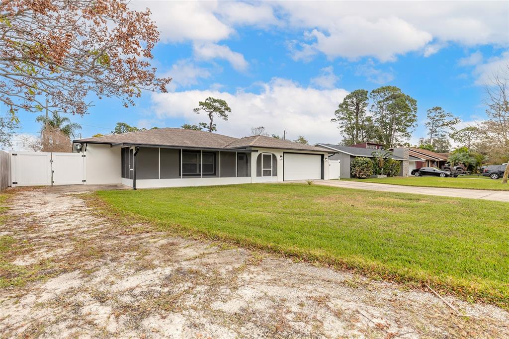 A single-story house with a screened-in porch, a two-car garage, and a large front lawn — 2509 MILTON AVENUE, NEW SMYRNA BEACH, FL