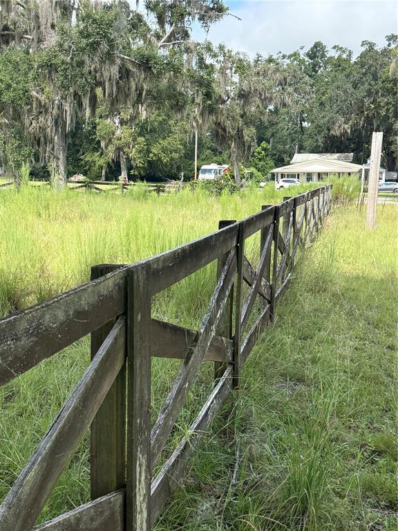 A wooden fence runs through a grassy field toward a house and trees in the distance — 16817 NW STATE ROAD 45, HIGH SPRINGS, FL