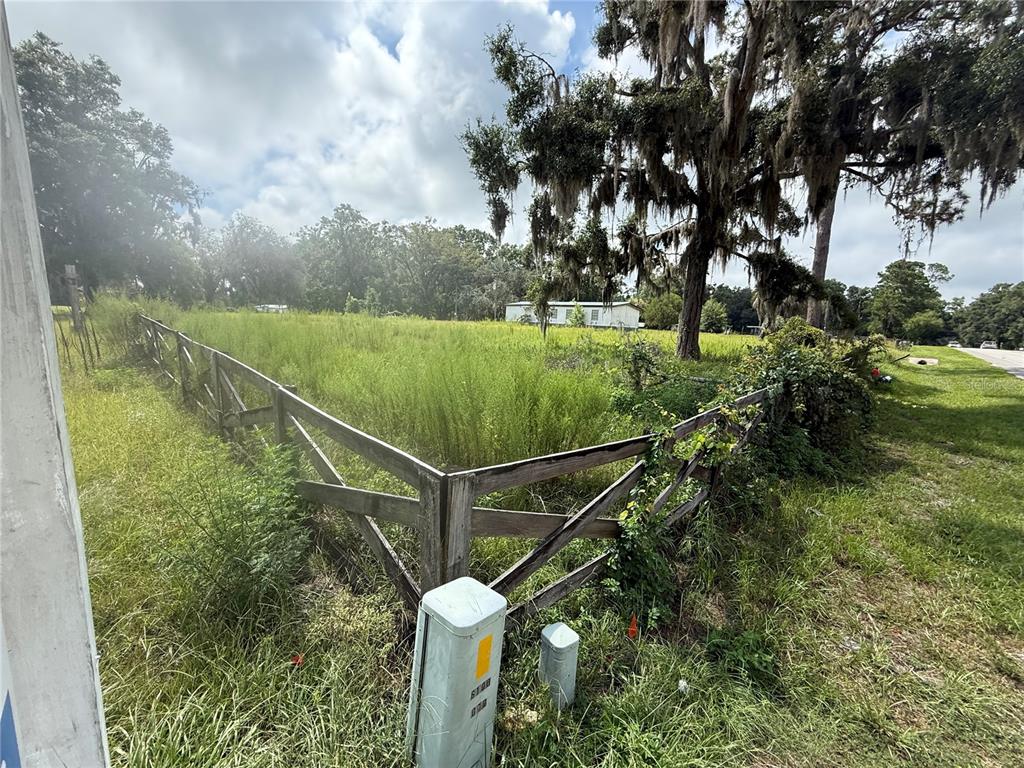 A fenced, grassy vacant lot features a large tree with Spanish moss and a distant house — 16817 NW STATE ROAD 45, HIGH SPRINGS, FL