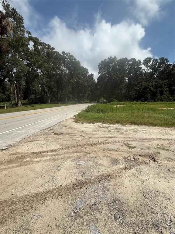 A paved road runs alongside a sandy lot bordered by a line of mature trees — 16817 NW STATE ROAD 45, HIGH SPRINGS, FL