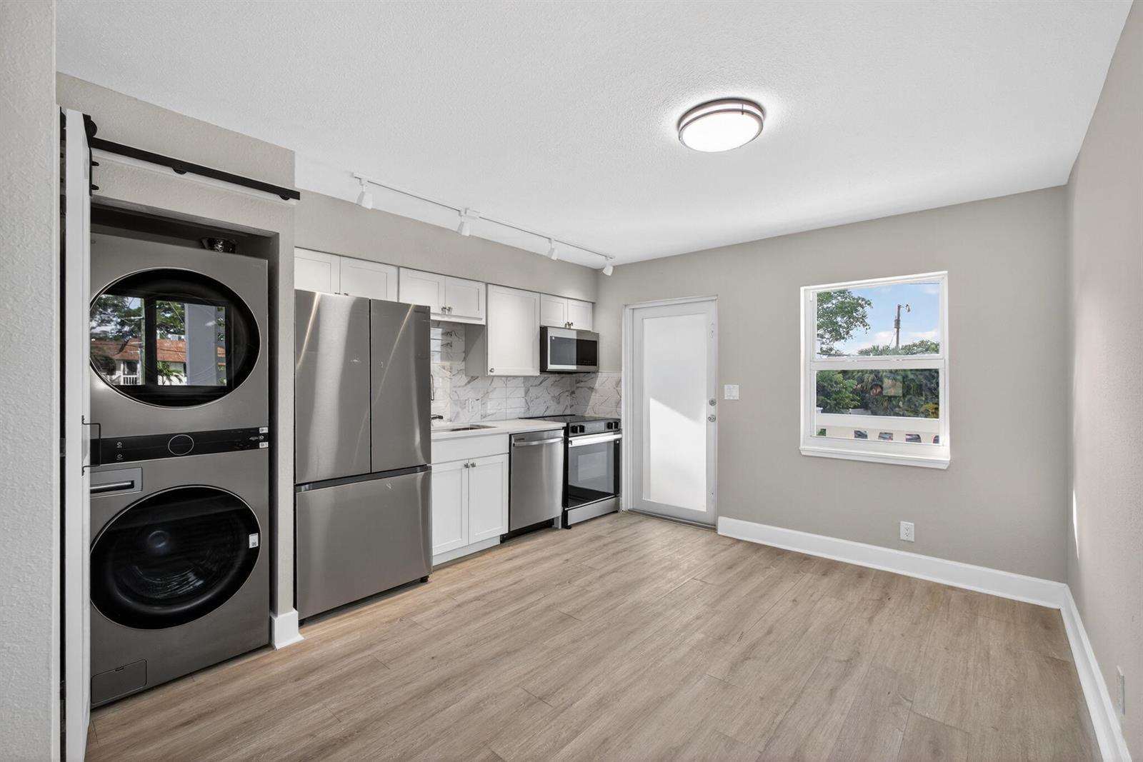 A kitchen with stainless steel appliances, white cabinets, and a stacked washer and dryer unit — 624 Southwind Circle # 2, North Palm Beach FL 33408, NORTH PALM BEACH, FL