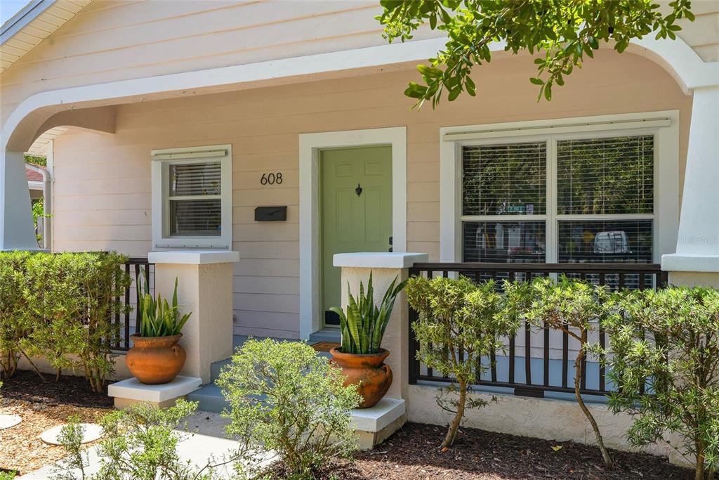 A light-colored bungalow with a front porch, white picket fence, and green front door — 608 9TH AVENUE N, ST PETERSBURG, FL