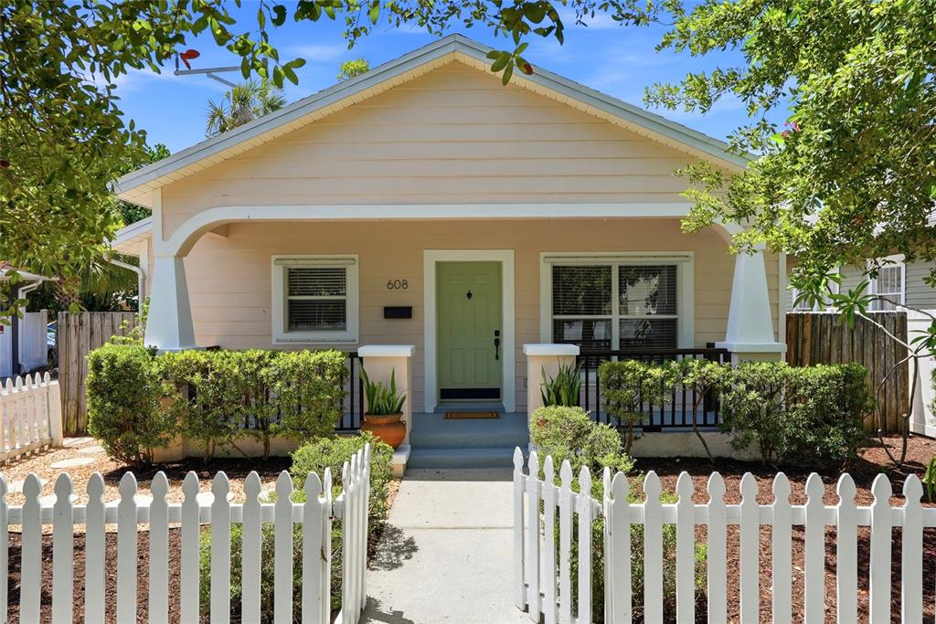A light-colored house exterior features a green front door, a porch, and potted plants — 608 9TH AVENUE N, ST PETERSBURG, FL