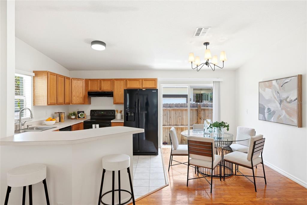 A kitchen with wood cabinets, black appliances, and a dining area with a glass table — 608 9TH AVENUE N, ST PETERSBURG, FL