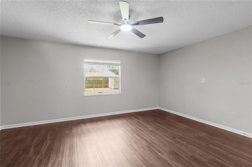 An empty bedroom features light gray walls, wood-look flooring, and a ceiling fan — 2417 ROSLYN LANE, LAKELAND, FL