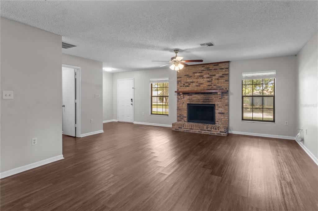 A living room features wood-look flooring, a brick fireplace, and a ceiling fan — 2417 ROSLYN LANE, LAKELAND, FL