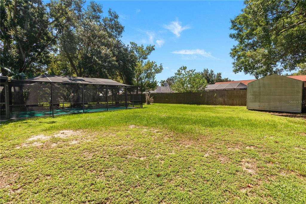 A large backyard features a screened-in pool enclosure, a storage shed, and a wooden fence — 2417 ROSLYN LANE, LAKELAND, FL
