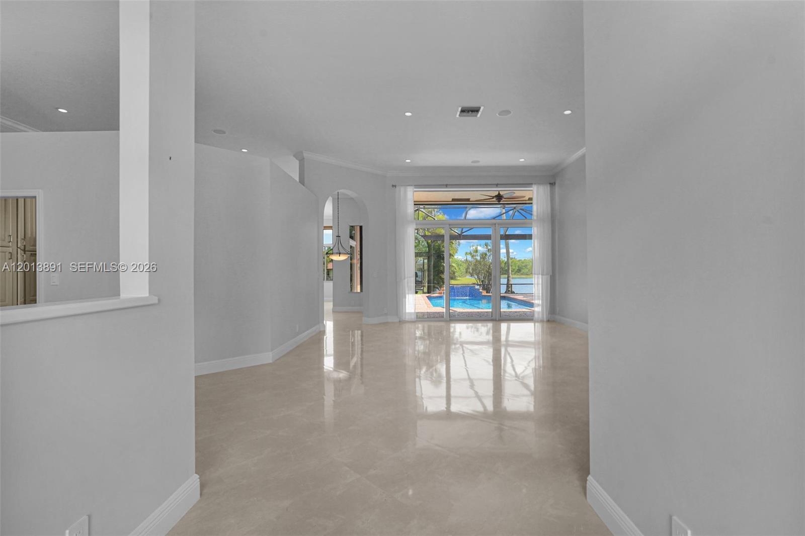 An open living area features light tile floors, recessed lighting, and sliding glass doors to a pool — 2715 Edgewater Court, Weston FL 33332, WESTON, FL