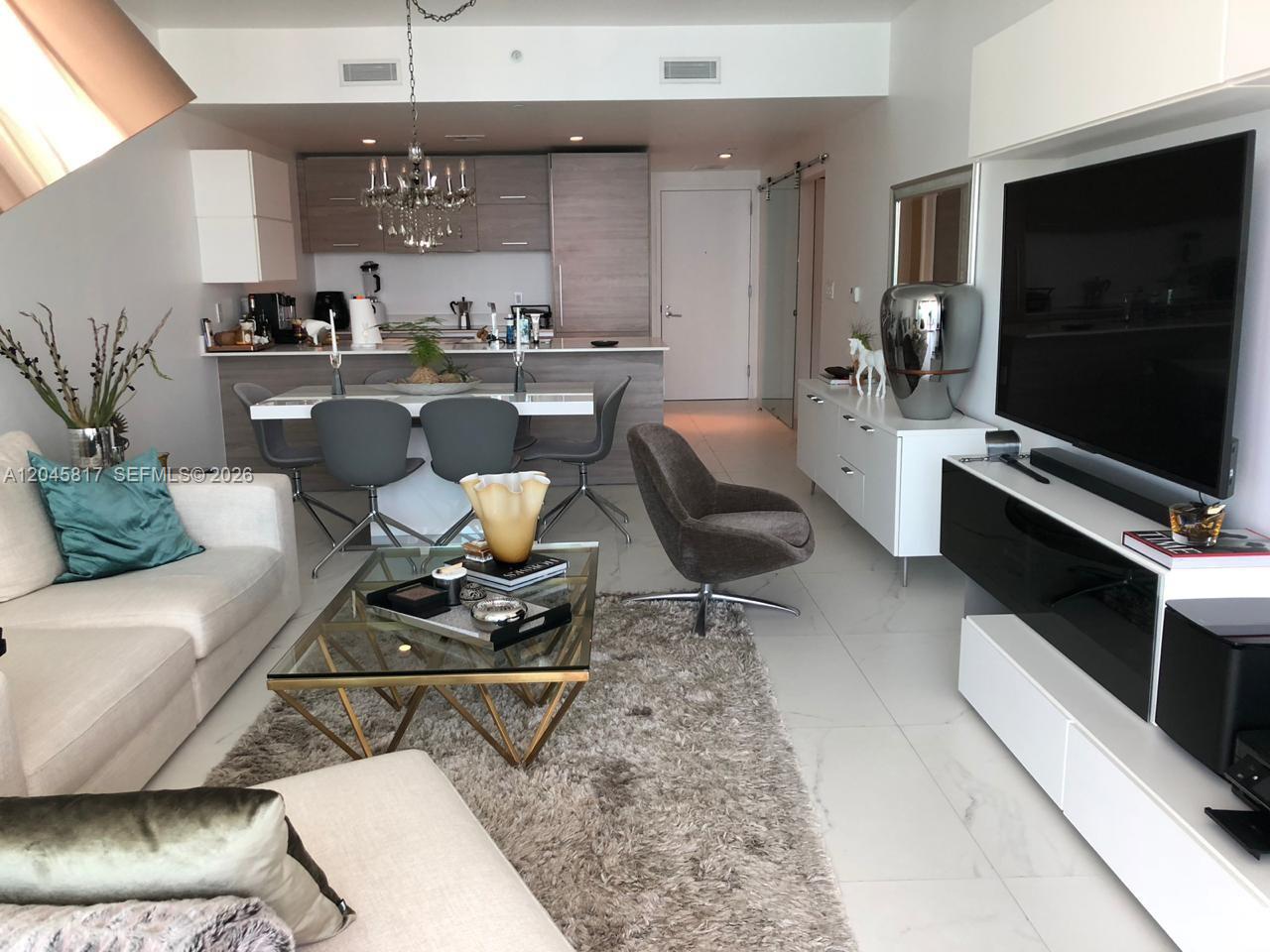 This open-concept living and dining area features modern furniture, a glass coffee table, and tile flooring — 1300 S Miami Ave # 3703, Miami FL 33130, MIAMI, FL