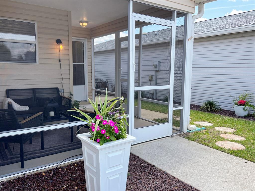 A screened-in patio features outdoor furniture, a white planter, and a view of a yard — 2146 ESTEVEZ DRIVE, THE VILLAGES, FL