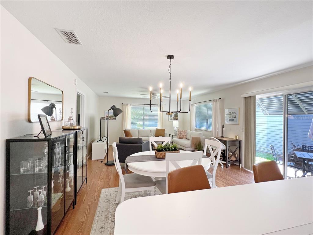 An open-concept dining and living area features a round table, chandelier, and hardwood flooring — 2146 ESTEVEZ DRIVE, THE VILLAGES, FL