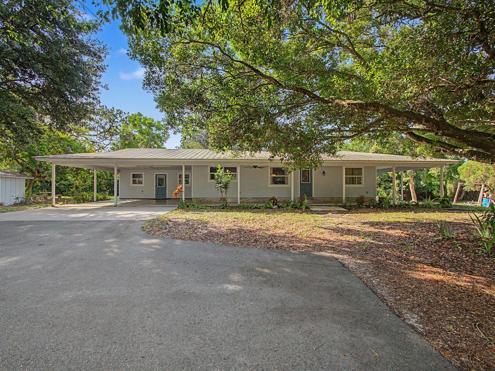 A single-story house with a metal roof, a large carport, and a paved driveway — 5625 SE Ault Avenue, Stuart FL 34997, STUART, FL