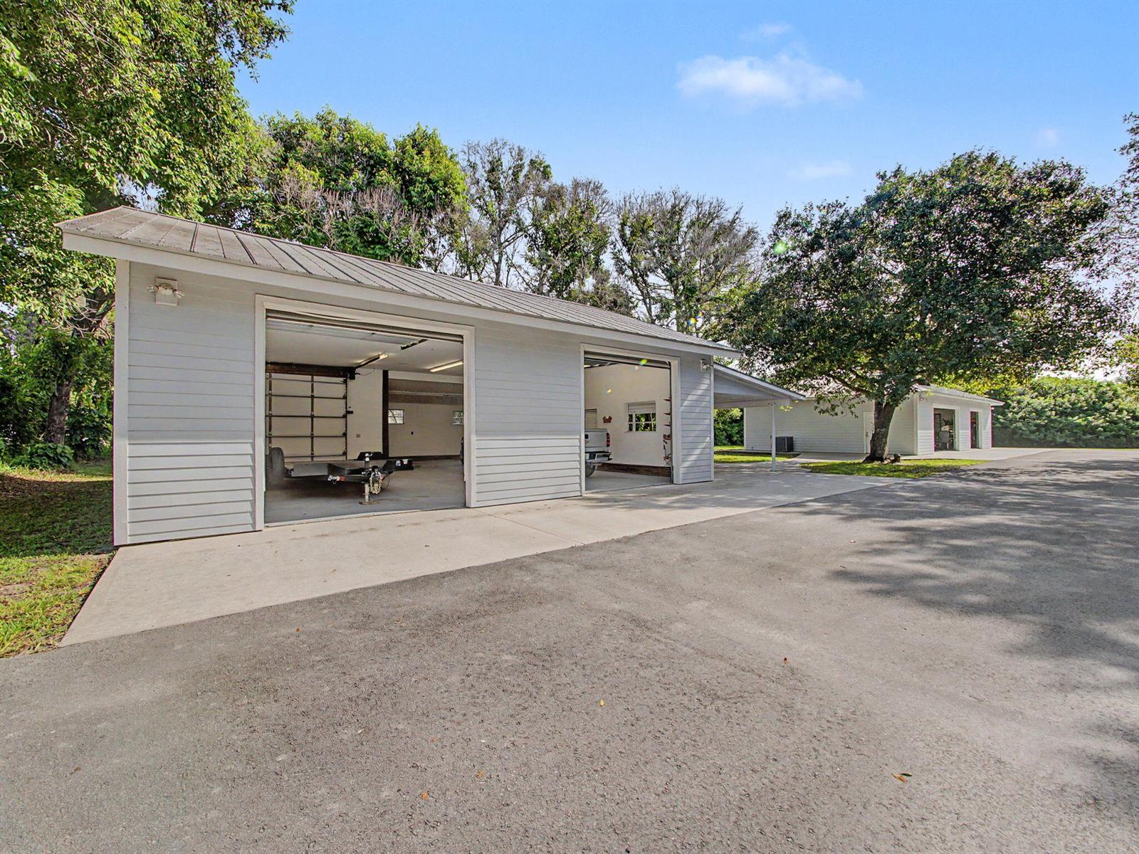 A detached garage with two open bays and a metal roof sits on a paved lot — 5625 SE Ault Avenue, Stuart FL 34997, STUART, FL