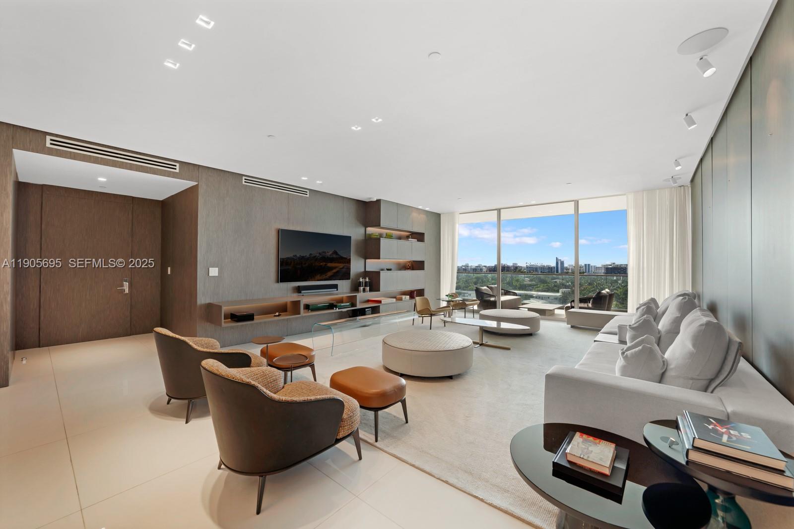 A modern living room features wood-paneled walls, a large sofa, armchairs, and floor-to-ceiling windows — 10201 Collins Ave # 807, Bal Harbour FL 33154, BAL HARBOUR, FL