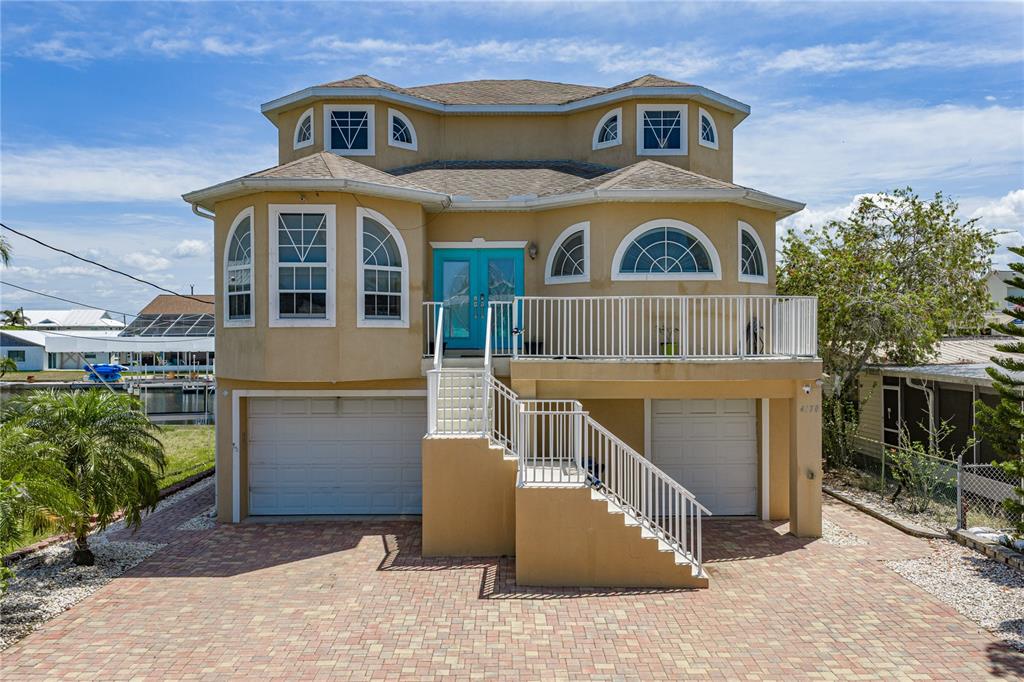 A two-story house with a tan exterior, two garage doors, and a front staircase — 4178 DES PREZ COURT, HERNANDO BEACH, FL