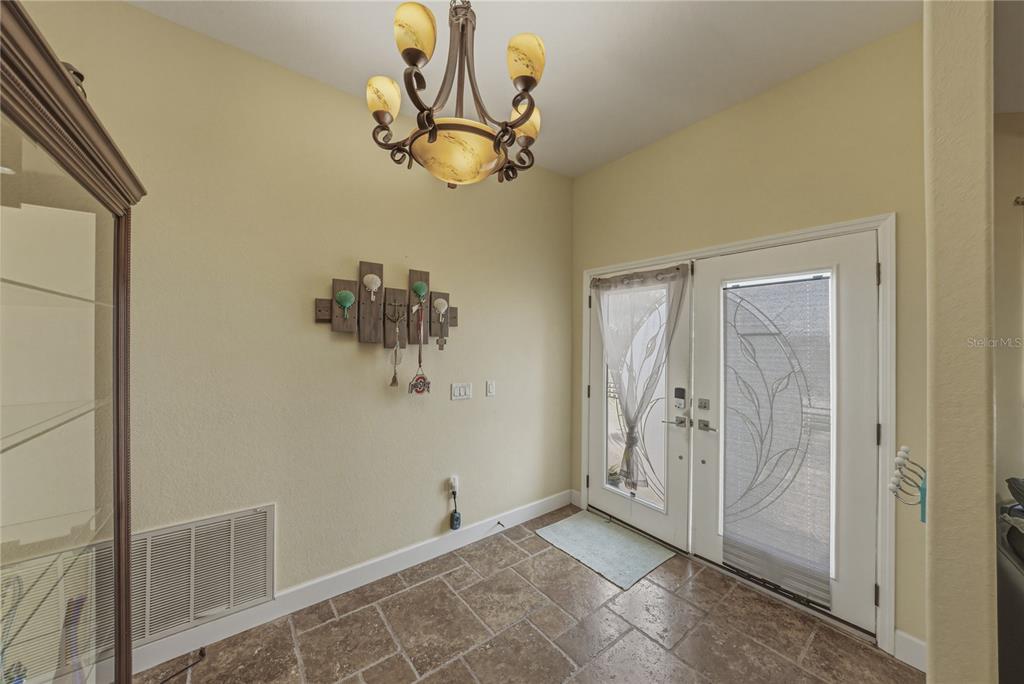 An entryway features tile flooring, a chandelier, a wall-mounted coat rack, and double glass doors — 4178 DES PREZ COURT, HERNANDO BEACH, FL