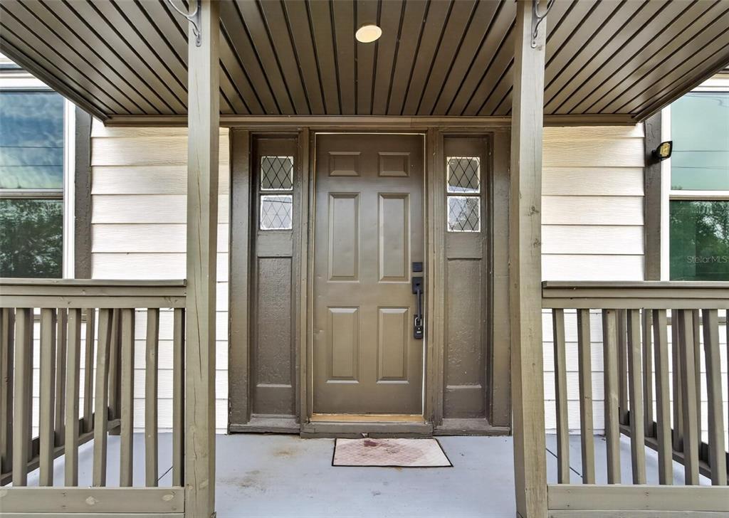 A brown front door with sidelights is centered on a covered porch with railings — 1900 16TH STREET S, ST PETERSBURG, FL