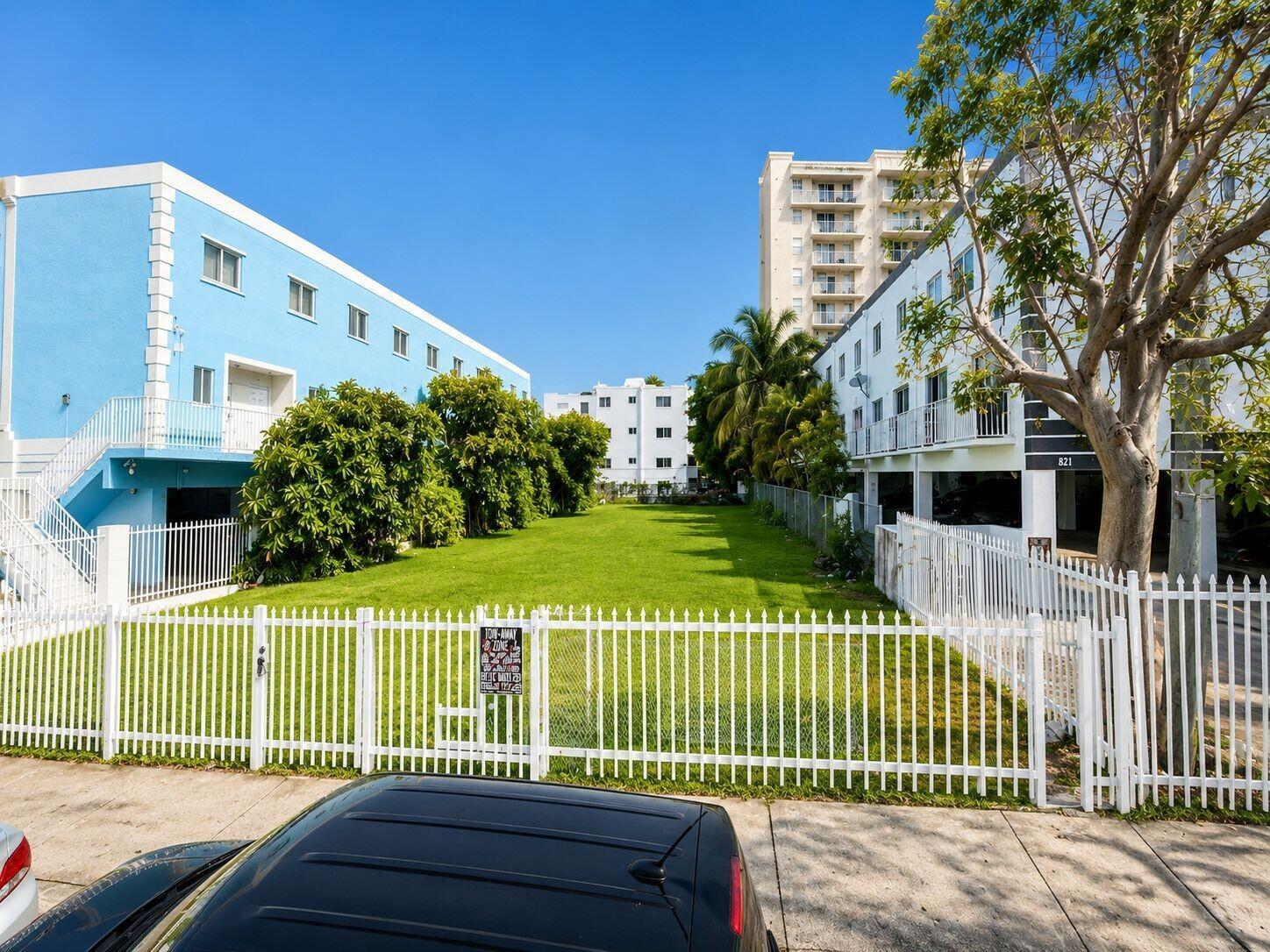 A grassy vacant lot sits between two multi-story apartment buildings behind a white metal fence — 829 SW 2nd Street, Miami FL 33130, MIAMI, FL