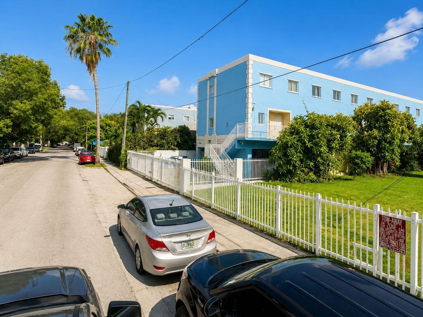 A blue multi-story apartment building sits behind a white fence along a residential street — 829 SW 2nd Street, Miami FL 33130, MIAMI, FL