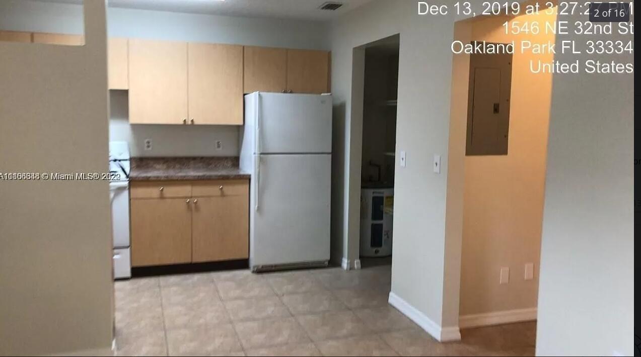 A kitchen features light wood cabinets, a white refrigerator, and tiled flooring — OAKLAND PARK, FL