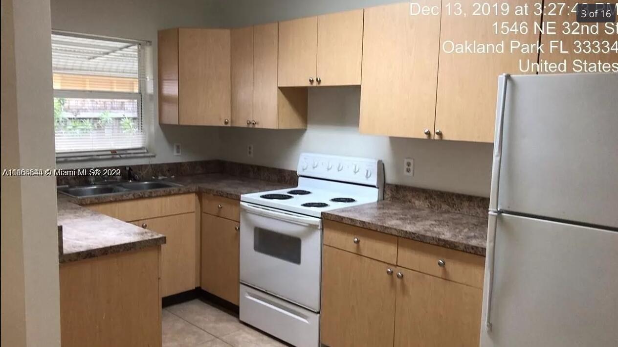 A kitchen features light wood cabinets, laminate countertops, a white stove, and a white refrigerator — OAKLAND PARK, FL