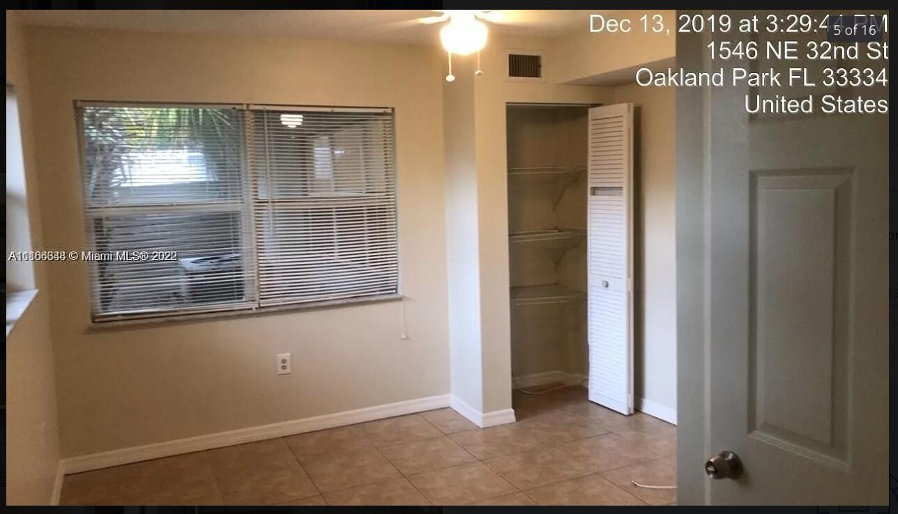An empty room features beige walls, tile flooring, a window with blinds, and a closet — OAKLAND PARK, FL