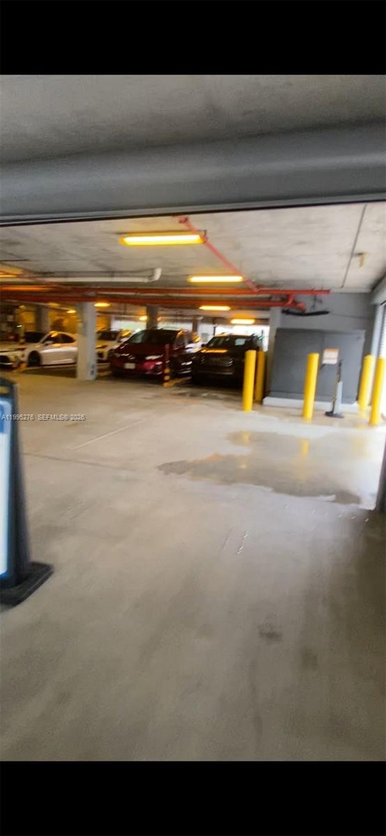 This is a parking garage with concrete floors, overhead lighting, and several parked vehicles — 1215 W Ave Parking, Miami Beach FL 33139, MIAMI BEACH, FL