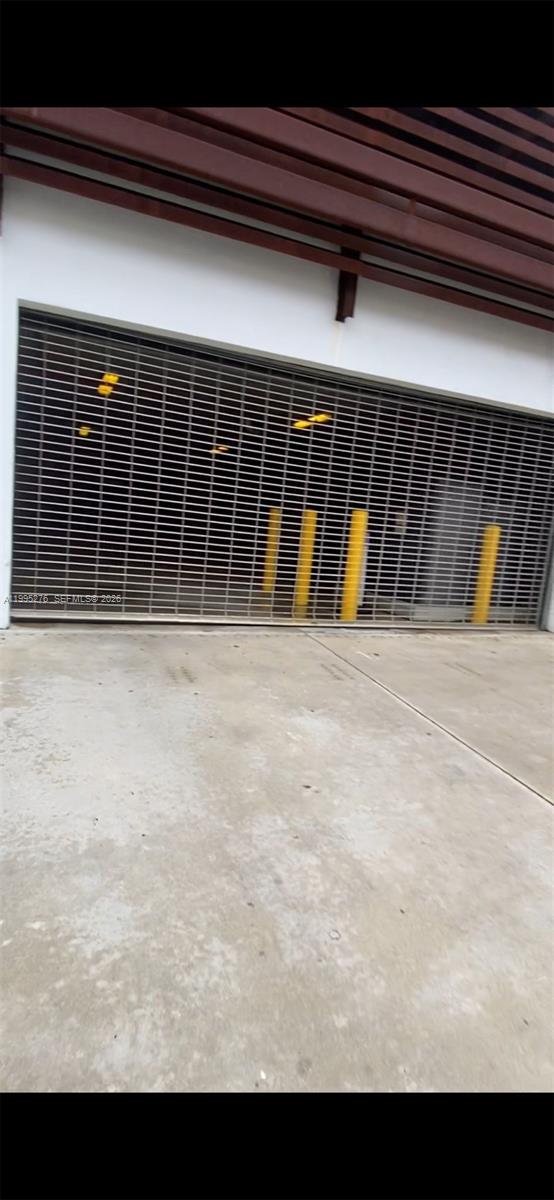 A metal security gate covers the entrance to a parking garage with yellow bollards — 1215 W Ave Parking, Miami Beach FL 33139, MIAMI BEACH, FL
