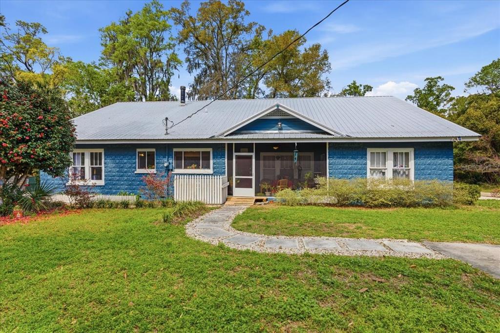 A blue, single-story house with a metal roof and a front porch sits on grass — 18708 NW 242ND STREET, HIGH SPRINGS, FL