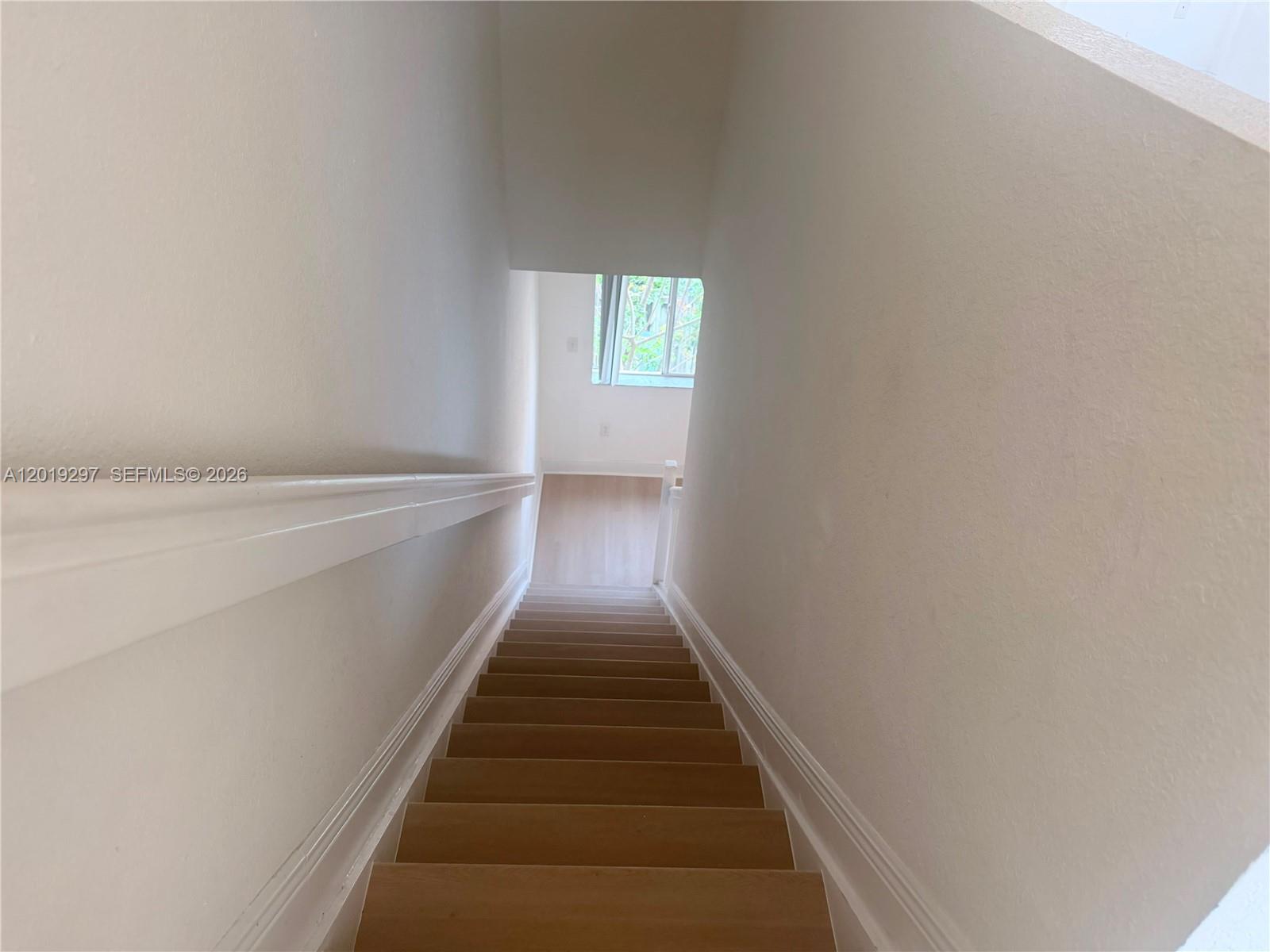 An empty room features light wood-look flooring, white walls, and a single window — 7989 NW 8th St # 107D, Miami FL 33126, MIAMI, FL