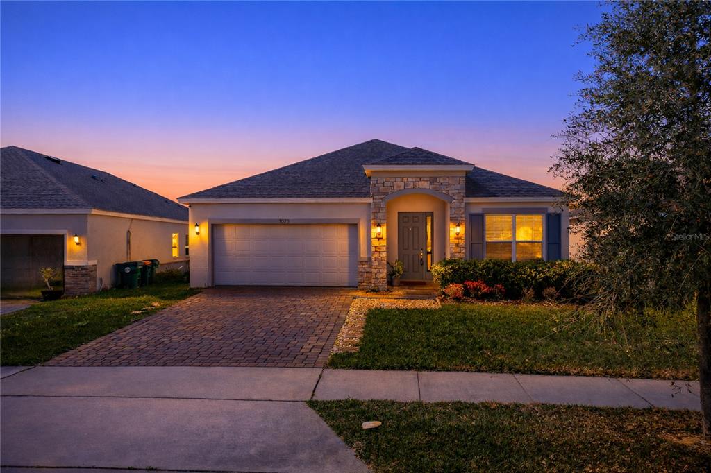 A single-story suburban house features a stone-accented entryway, a two-car garage, and a paved driveway — 1073 CHELAN FALLS DRIVE, DELAND, FL