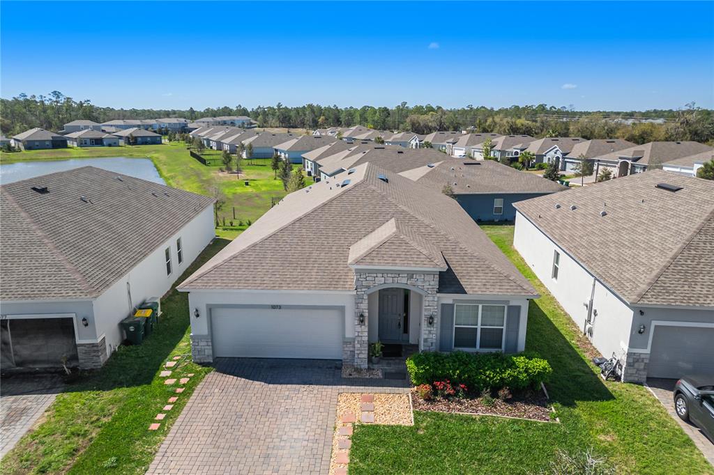 An aerial view shows a single-story suburban house with a paved driveway and shingled roof — 1073 CHELAN FALLS DRIVE, DELAND, FL