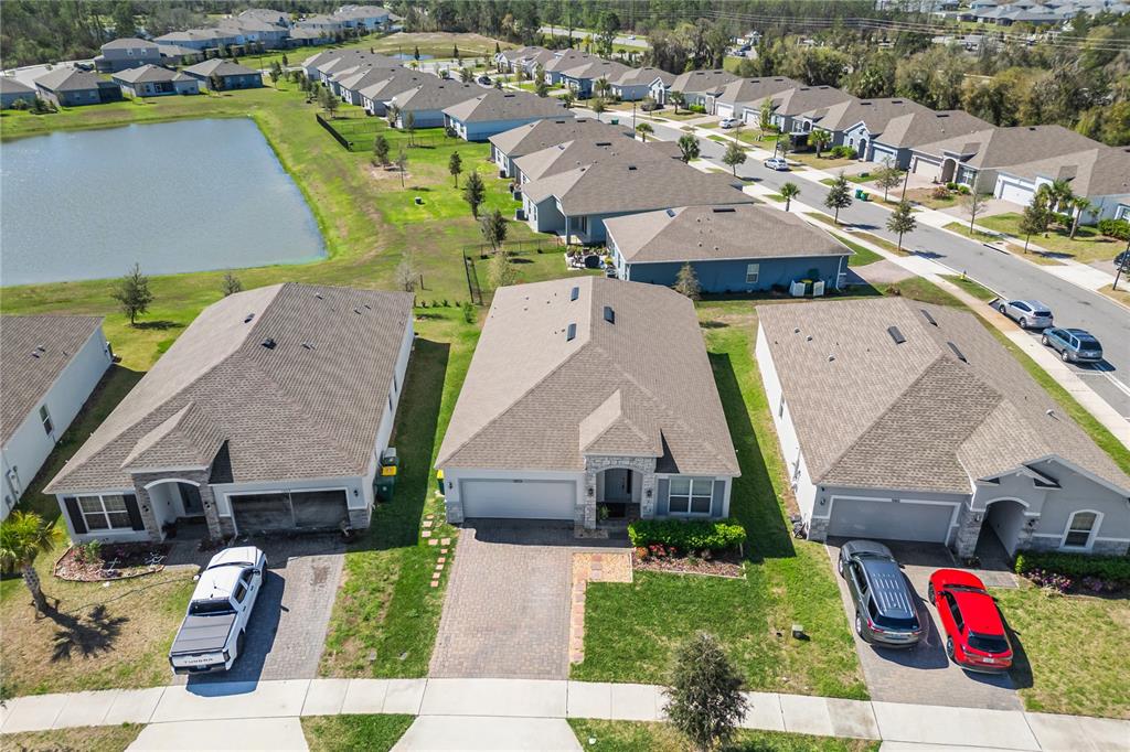 An aerial view shows three suburban houses with driveways and a nearby pond — 1073 CHELAN FALLS DRIVE, DELAND, FL