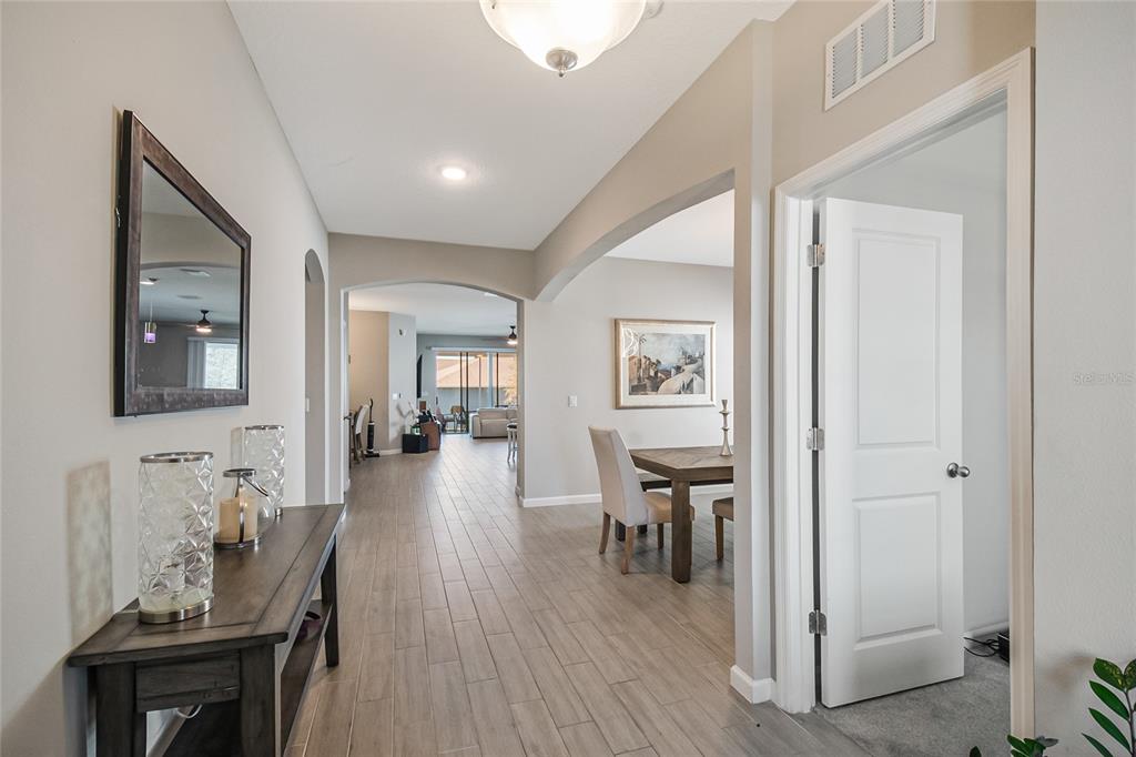 A hallway with light wood-look tile flooring leads toward an open dining and living area — 1073 CHELAN FALLS DRIVE, DELAND, FL