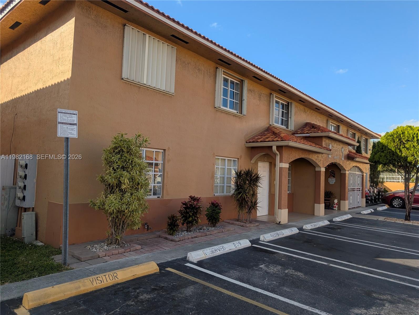 A two-story tan stucco apartment building with a tiled roof and designated parking spaces — 2485 W 76th St # 109, Hialeah FL 33016, HIALEAH, FL