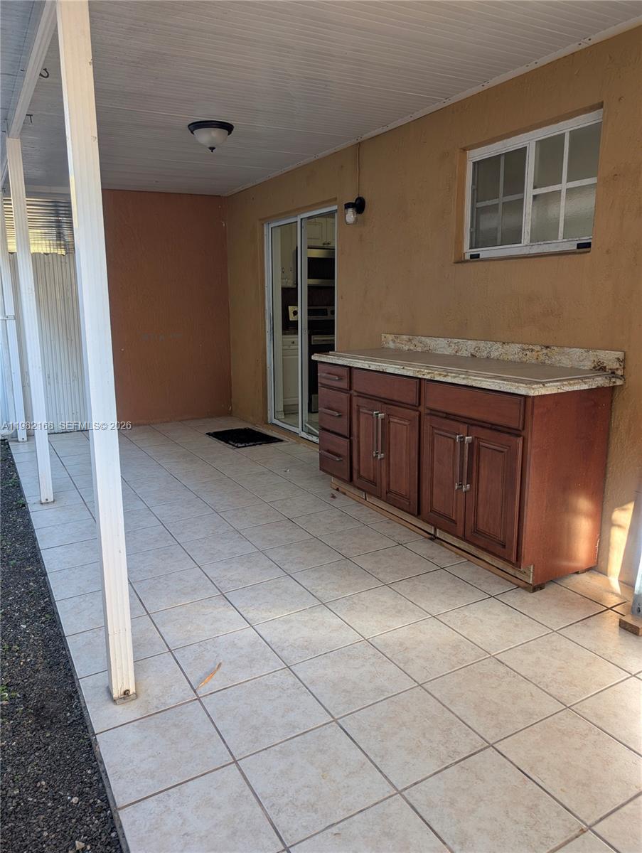 A covered patio features tiled flooring, a granite-topped wooden cabinet, and a sliding glass door — 2485 W 76th St # 109, Hialeah FL 33016, HIALEAH, FL