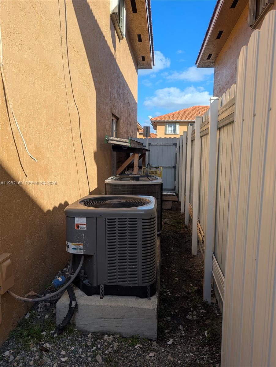 Two air conditioning units sit on a concrete pad in a narrow side yard — 2485 W 76th St # 109, Hialeah FL 33016, HIALEAH, FL