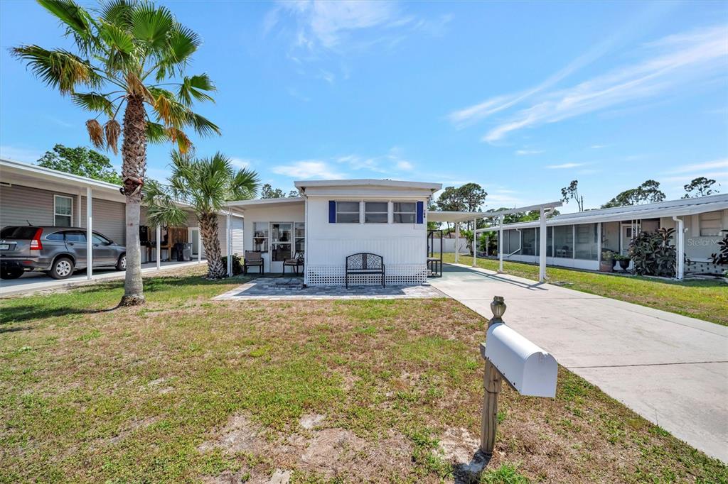 A white mobile home with a paved front patio, carport, and a mailbox in the yard — 264 S PORT ROYAL LANE, APOLLO BEACH, FL