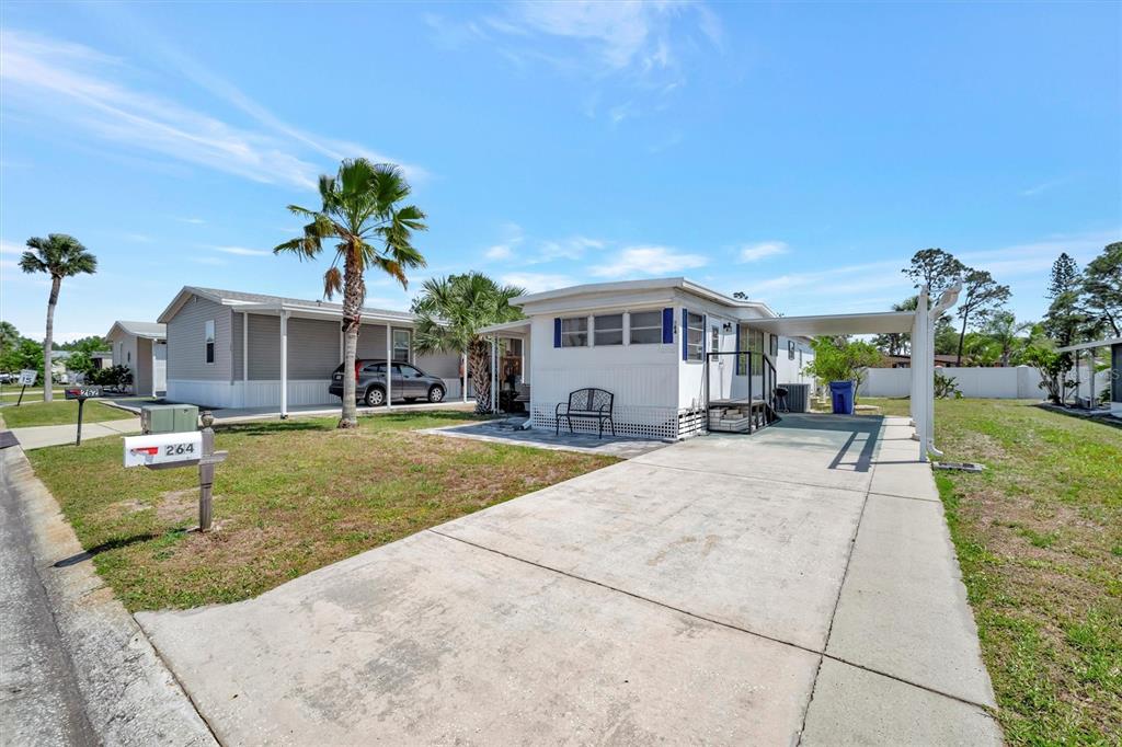 A white mobile home features a concrete driveway, a carport, and a small front yard — 264 S PORT ROYAL LANE, APOLLO BEACH, FL