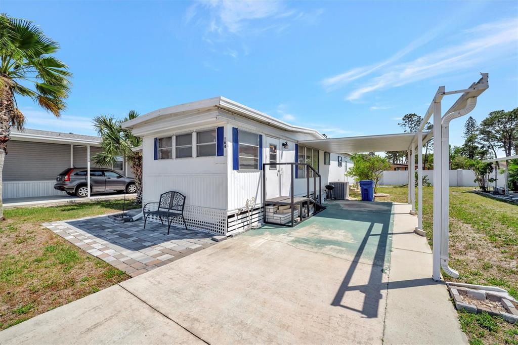 A white mobile home features a paved patio, a covered carport, and a metal staircase — 264 S PORT ROYAL LANE, APOLLO BEACH, FL