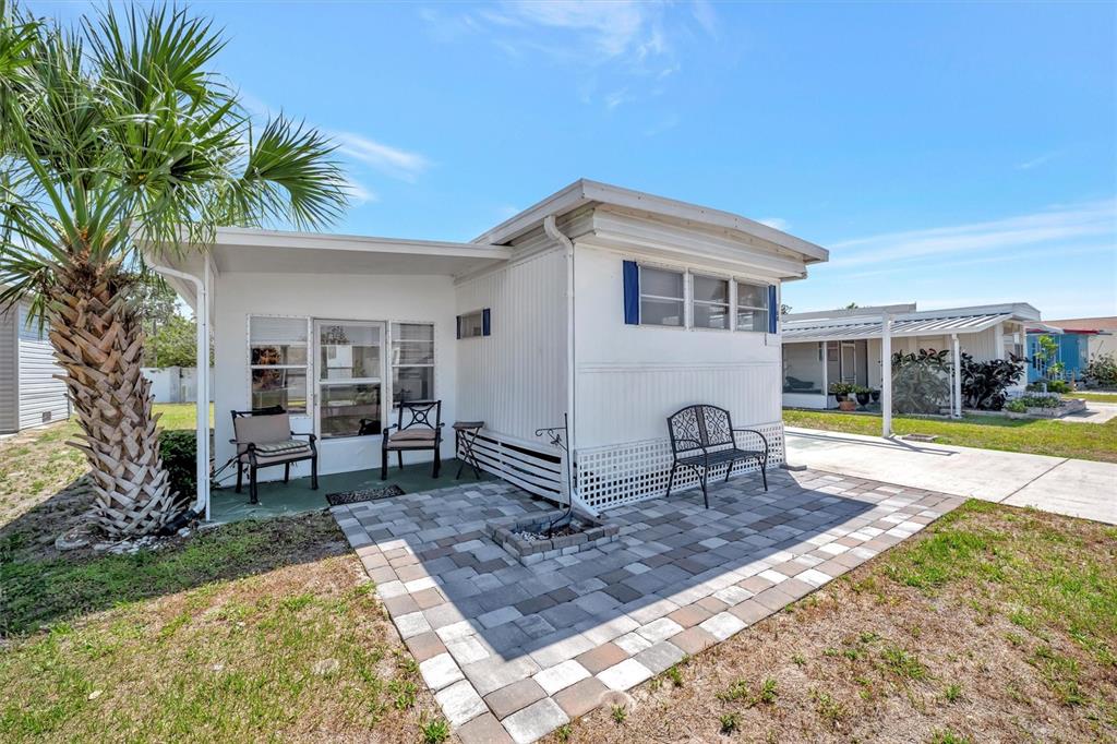 A white mobile home features a paved patio area, outdoor seating, and a palm tree — 264 S PORT ROYAL LANE, APOLLO BEACH, FL
