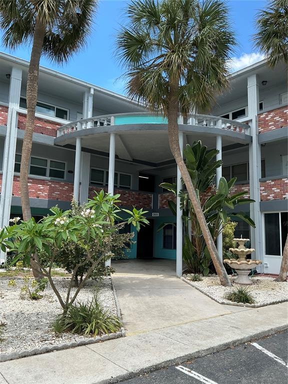 An exterior view of a multi-story apartment building with palm trees and a small fountain — 4300 58TH STREET N UNIT 1913, KENNETH CITY, FL
