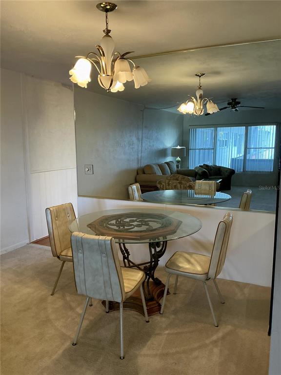 A dining area features a glass-topped table, four chairs, and a large wall mirror — 4300 58TH STREET N UNIT 1913, KENNETH CITY, FL