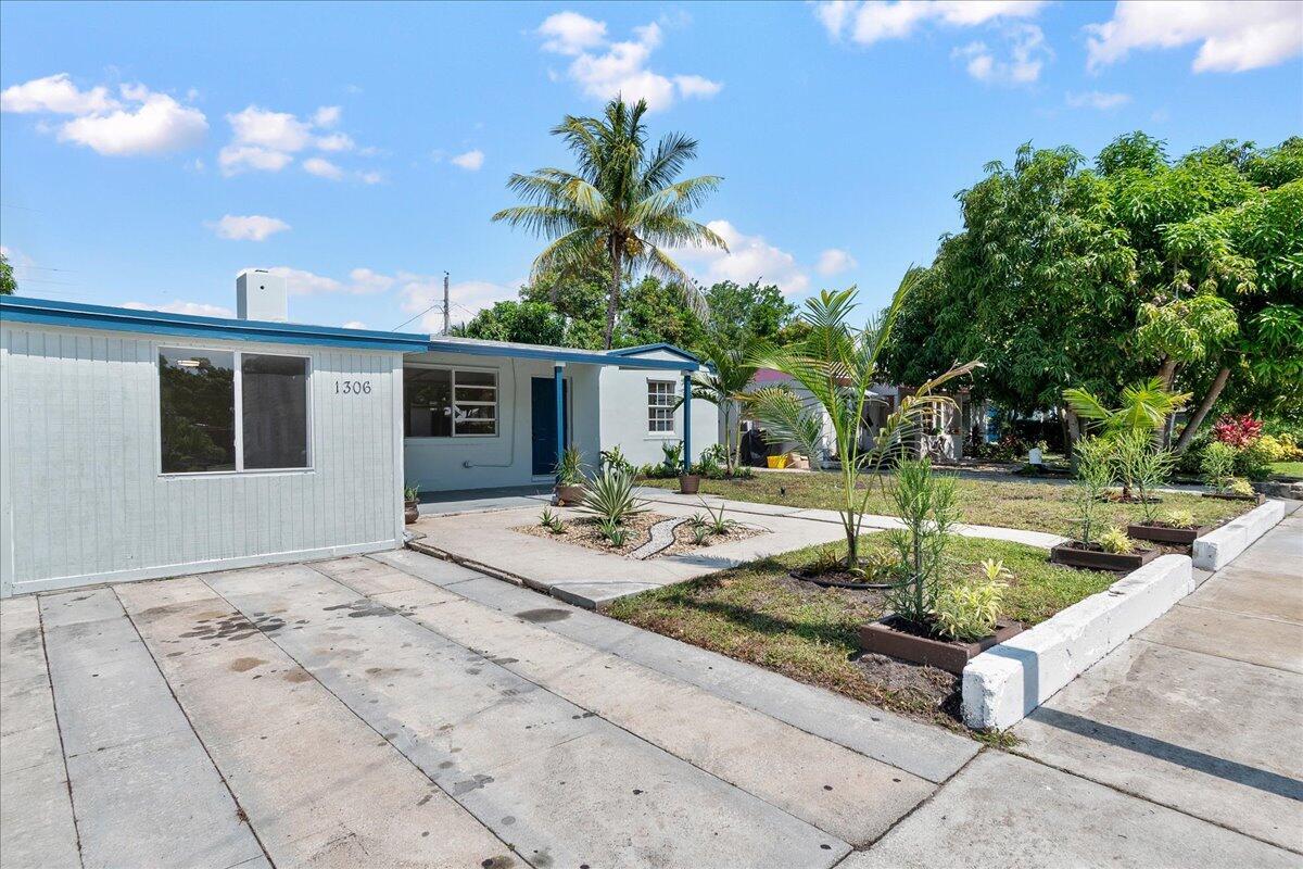 A single-story house with a concrete driveway, a small front yard, and palm trees — 1306 S C Terrace, FL 33460, FL