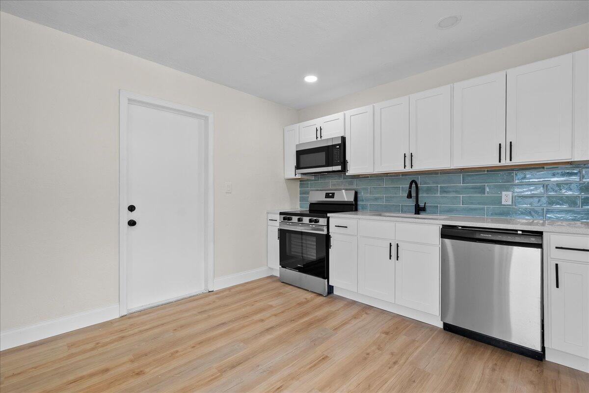 A kitchen features white cabinets, stainless steel appliances, and a blue subway tile backsplash — 1306 S C Terrace, FL 33460, FL